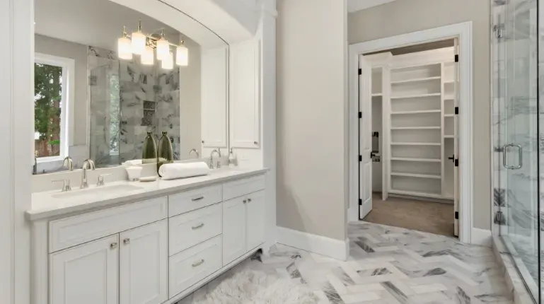 bathroom remodel with marble flooring and white accent cabinets